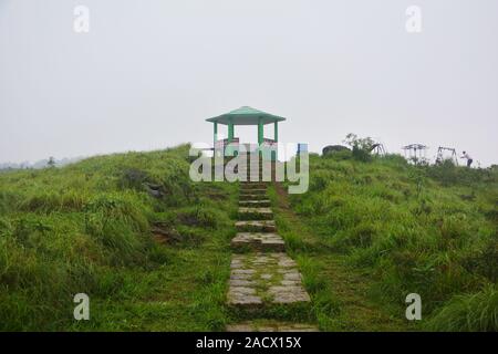 Il famoso passo concreto, gazebo, pavilion di Cherrapunjee eco park con 1/3 di un muro di mattoni, pilastri e tetto in pietra e percorso verde erbe e nebbioso sky Foto Stock