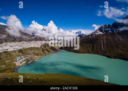 Antenna di panoramica vista sul lago di Gokyo, Ngozumpa glacier e il villaggio dal vertice di Gokyo Ri, monsone di nuvole che si muovono in Foto Stock