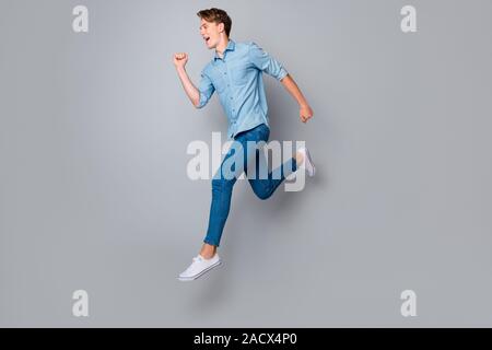 A piena lunghezza profilo foto a lato del ragazzo entusiasta jump eseguire desidera acquistare la fretta venerdì nero occasioni usura stile casual abbigliamento sneakers isolate su Foto Stock
