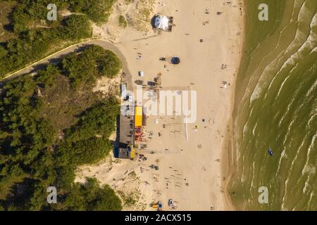 Antenna vista dall'alto in basso di frantumazione onde su una spiaggia di sabbia con le persone a prendere il sole. Foto Stock