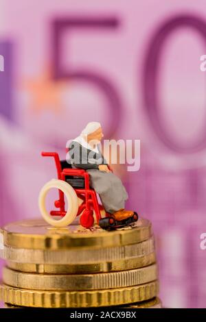 Una donna su una sedia a rotelle su un mucchio di soldi Foto Stock