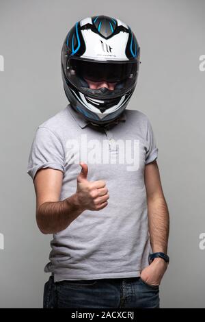 Uomo che indossa il casco del motore che mostra segno ok Foto Stock