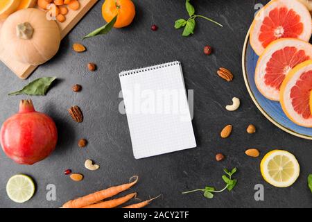 Cibo, mangiare sano e la dieta concetto - close up di notebook, di frutta e verdura sulla tavola di ardesia top Foto Stock