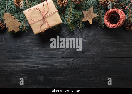 Telaio di natale di rami di abete, articoli da regalo e giocattoli in legno scuro sulla tavola di legno. Vista dall'alto. Spazio per il testo. Rifiuti Zero vacanza. Eco-compatibile. Foto Stock