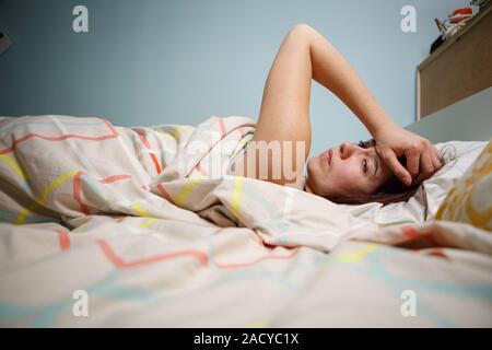 Vista laterale di una sonnolenta di giovane donna che soffre di mal di testa con gli occhi chiusi nel letto di casa Foto Stock