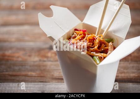 Tagliatelle con carne di maiale e le verdure in take-out box sul tavolo di legno Foto Stock