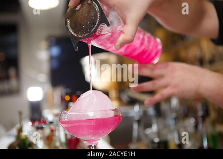 Close-up di barman versa manualmente rosa cocktail drink nel bar Foto Stock