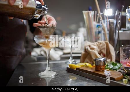 Barista coocks cocktail dietro un banco di bar Foto Stock