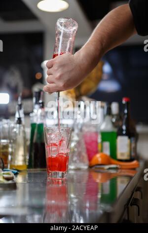 Barista coocks cocktail dietro un banco di bar Foto Stock