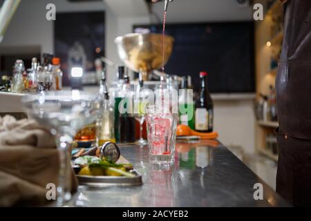 Barista coocks cocktail dietro un banco di bar Foto Stock