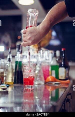 Barista coocks cocktail dietro un banco di bar Foto Stock