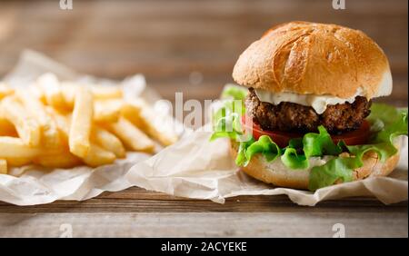 In casa hamburger e patatine fritte su un piatto di legno Foto Stock