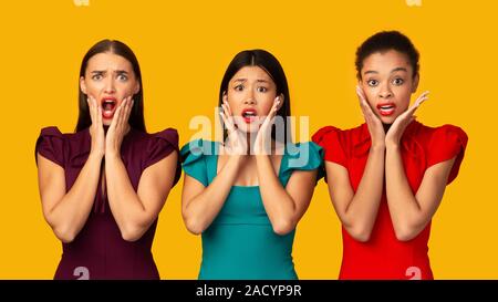 Tre ragazze scontente urlando in piedi sul giallo di sfondo per studio, Panorama Foto Stock