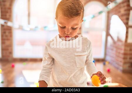 Bella bionda toddler giocando in plastica con cibi e piatti. Piedi intorno un sacco di giocattoli a kindergarten Foto Stock