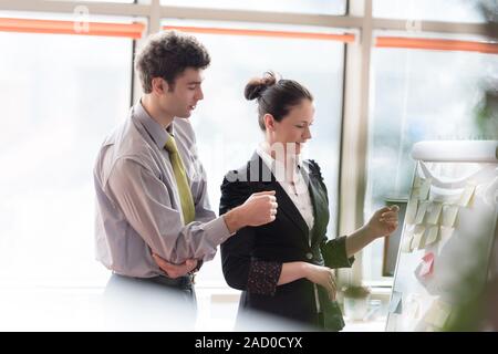 Coppia giovane lavorando sul flip board in ufficio Foto Stock