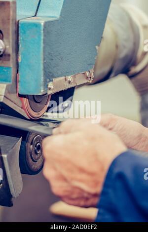 Le mani di un calzolaio esperto utilizzando una speciale macchina utensile per la realizzazione di calzature. Pattino del processo di produzione in fabbrica. Messa a fuoco selettiva Foto Stock