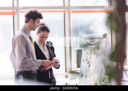 Coppia giovane lavorando sul flip board in ufficio Foto Stock