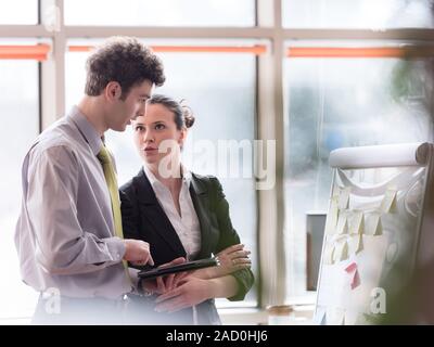 Coppia giovane lavorando sul flip board in ufficio Foto Stock