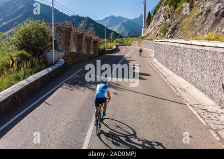 L'uomo è in sella ad una bicicletta. Una montagna di strada a serpentina. Il Kazakistan, Almaty, Medeo Foto Stock