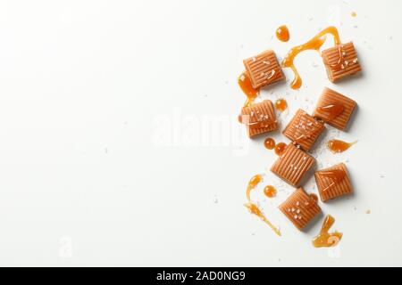 Salate caramelle di caramello e salsa su sfondo bianco, spazio per il testo Foto Stock