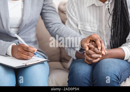 Irriconoscibile councelor femmina consolante la sua emotivo paziente, tenendo la mano Foto Stock