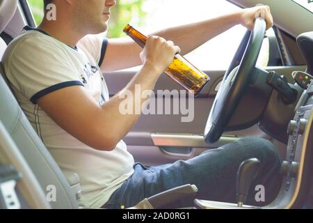 Uomo di bere birra mentre si guida la macchina. Foto Stock