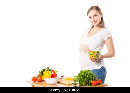 Felice donna incinta con coppa di verdure Foto Stock