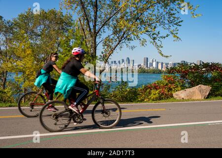 Montreal, CA - 21 Settembre 2019 : due donne equitazione biciclette, sull'isola di Notre Dame, con lo skyline di Montreal in background. Foto Stock