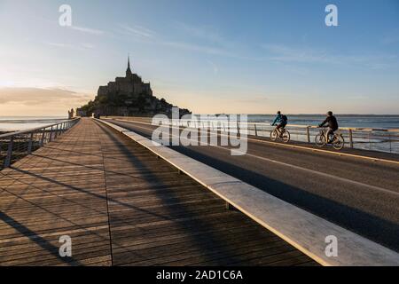 I ciclisti attraversando il ponte al Mont Saint Michel, in Normandia, Francia Foto Stock