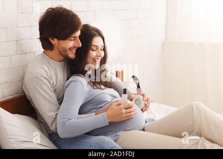 Ci aspettavamo giovane azienda cuffie sul ventre in gravidanza la riproduzione di musica di baby Foto Stock