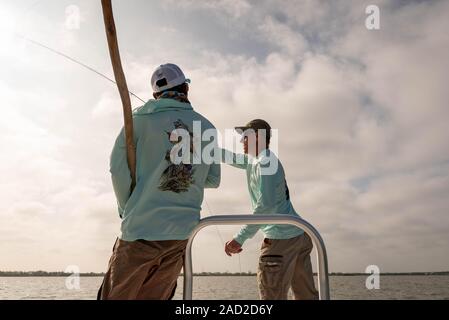 Ambergris Caye Belize - Novembre, 16, 2019. Local guida di pesca incarica un pescatore a mosca sulla tecnica di colata utilizzati nella pesca di acqua salata come egli stan Foto Stock