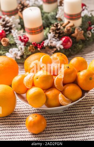 I mandarini e le arance sulla tavola del Natale con la corona di Avvento Foto Stock