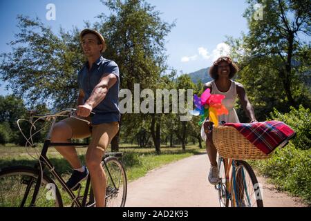 Giovane coppia multietnica avente un giro in bici nella natura Foto Stock