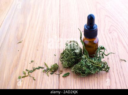 Medicinali marijuana cannabis con olio estratto in una bottiglia. cannabis CBD olio prodotti di canapa. Olio di cannabis con estratti di foglie di canapa sul tavolo di legno Foto Stock