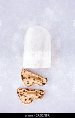 Vista dall'alto di una casalinga, stollen tedesco Christstollen con ripieno di marzapane, tagliato a fette. Foto Stock