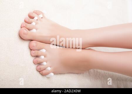 Piedi pedicure applicando una donna in piedi in separatori di punta Foto Stock