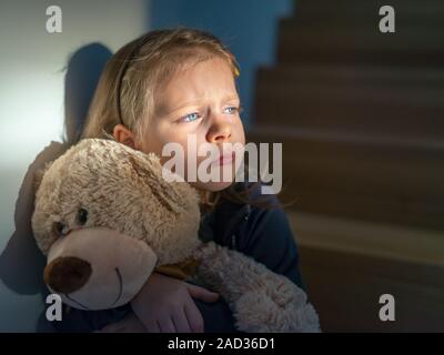 Triste bambina abbracciando il suo orsacchiotto - si sente isolato Foto Stock