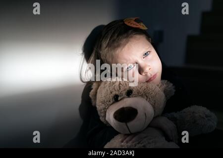 Triste bambina abbracciando il suo orsacchiotto - si sente isolato Foto Stock