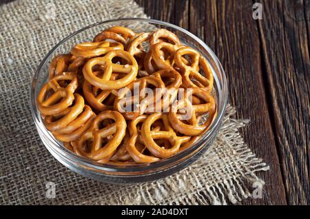 Piccolo pretzel salati in recipiente di vetro sul tavolo di legno Foto Stock