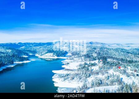 Inverno in Croazia. Panorama del lago Lokvarsko e boschi sotto la neve nella regione di Gorski kotar e Risnjak mountain in background da fuco. Foto Stock