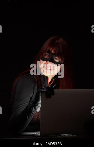 Ragazza in maschera con il computer portatile Foto Stock