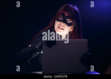 Bruna in maschera con il computer portatile Foto Stock