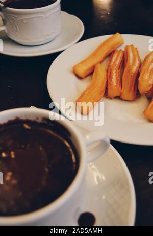 Due tazze di cioccolata calda e churros con zucchero Foto Stock
