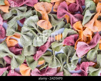 Pila di essiccato italiano Tricolore farfalle di pasta, sfondo vari colori del filtro bow tie Foto Stock