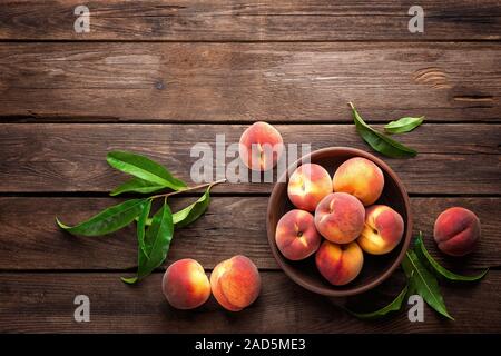 Fresche succose pesche con foglie sul legno scuro dello sfondo rustico Foto Stock