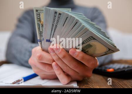 Mani caucasica conteggio banconote di dollari sul legno scuro tabella Foto Stock