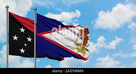 Papua Nuova Guinea e Isole Samoa americane bandiera sventolare nel vento contro bianco torbido cielo blu insieme. Concetto di Diplomazia e relazioni internazionali. Foto Stock