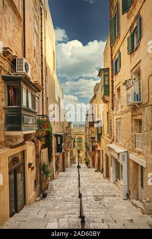 Strada stretta con scale a La Valletta, Malta, con case tradizionali Foto Stock