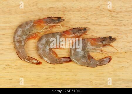 Tre materie gamberoni su un tagliere di legno Foto Stock