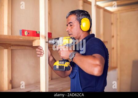 Tuttofare con cuffie giallo funziona con trapano non riparazione. Foto Stock